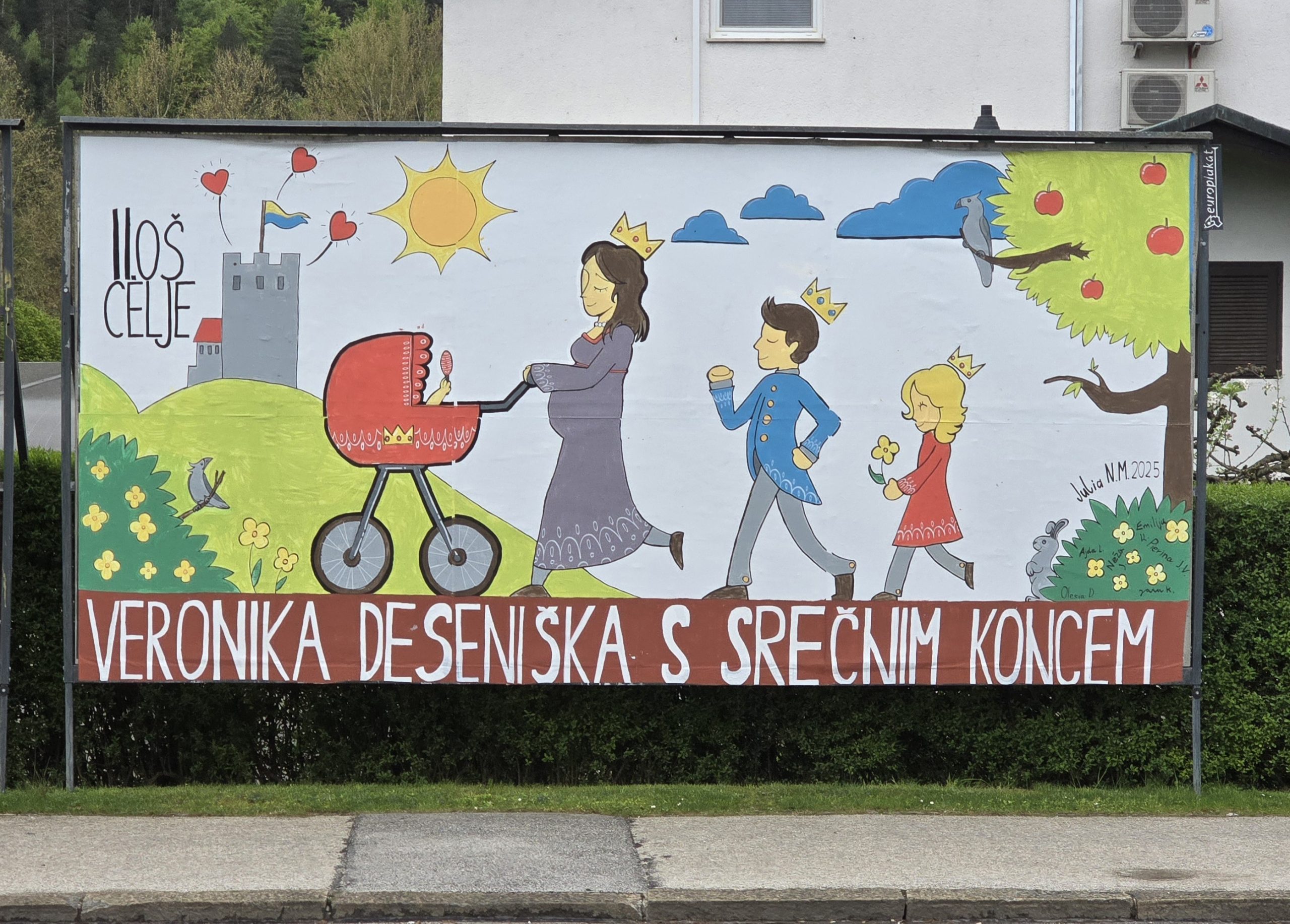 Jumbo plakat ob cesti. Na njem v koloni korakajo veronika desenjiška in dva otroka.